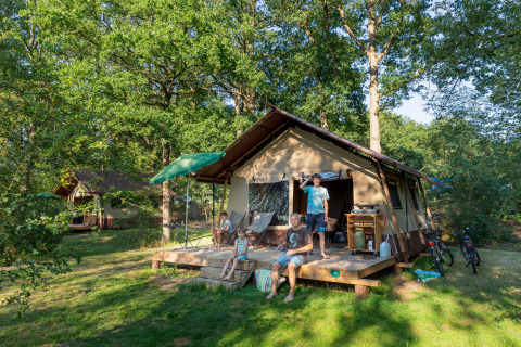 Gezin voor een glamping tent bij Camping Huttopia De Roos aan de Vecht in Overijssel, omringd door natuur.