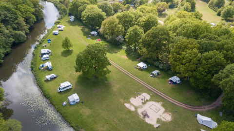Luchtfoto van Camping Huttopia De Roos aan de Vecht in Overijssel met tenten en campers verspreid.