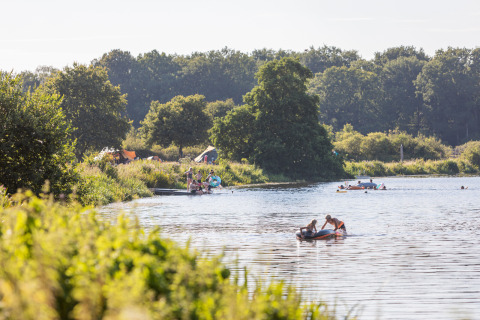 Camping Huttopia De Roos au bord de la rivière Vecht en Overijssel, Pays-Bas, avec campeurs et canoës.