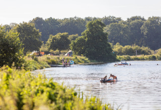 Camping Huttopia De Roos au bord de la rivière Vecht en Overijssel, Pays-Bas, avec campeurs et canoës.