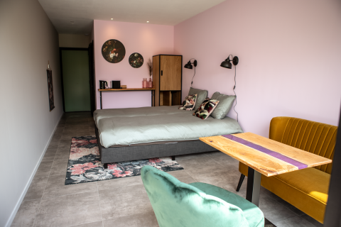 Modernes Glamping-Zimmer bei Landgoed Lindehof – Natuur Lodges Friesland mit rosa Wand und stilvollen Möbeln.