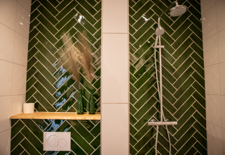 Moderne douche met groene wandtegels bij Landgoed Lindehof – Natuur Lodges Friesland glamping verblijf.