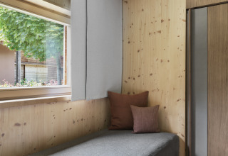 Innenaufnahme einer Holzhütte mit großen Fenstern und Kissen im Natürlich Hell Camping & Aparthotel - Tuin Lodges Tirol.