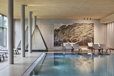 Innenpool mit modernen Liegestühlen und Zeltlodges im Natürlich Hell Camping & Aparthotel – Tuin Lodges Tirol.