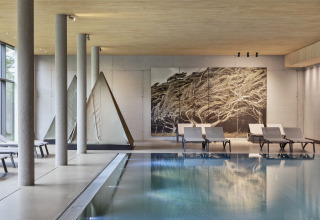 Espace piscine intérieure avec transats modernes et lodges tipi au Natürlich Hell Camping & Aparthotel à Tirol.