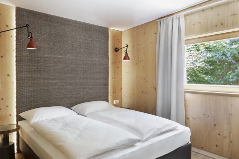 Modernes Glamping-Zimmer mit Doppelbett, Holzwänden und Fenster bei Natürlich Hell Camping & Aparthotel - Tuin Lodges Tirol.