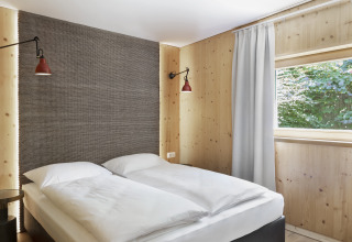 Hébergement glamping moderne avec lit double, murs en bois et fenêtre chez Natürlich Hell Camping & Aparthotel - Tuin Lodges Tirol.