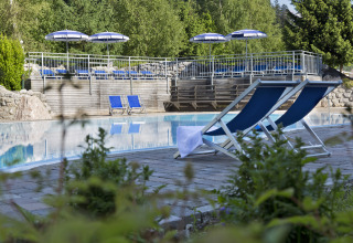 Udendørs poolområde med blå liggestole og parasoller på Natürlich Hell Camping & Aparthotel - Tuin Lodges Tirol.