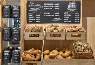 Assorted fresh breads and coffee selection displayed at Natürlich Hell Camping & Aparthotel - Tuin Lodges Tirol.