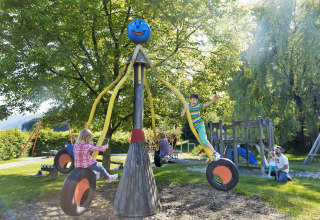 Kinder spielen auf einem Spielplatz mit Reifenschaukeln bei Natürlich Hell Camping & Aparthotel - Tuin Lodges Tirol.
