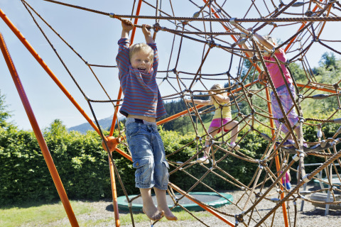 Kinder spielen an einem großen Kletternetz auf Natürlich Hell Camping & Aparthotel - Tuin Lodges Tirol.
