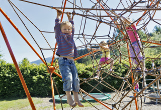 Children climbing a large rope structure outdoors at Natürlich Hell Camping & Aparthotel - Tuin Lodges Tirol.