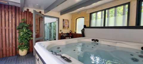 Espace spa intérieur avec jacuzzi et grandes fenêtres aux Truffières de Dordogne – La Bouquerie – Safaritenten.