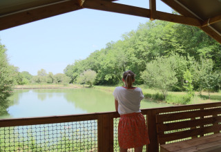 Mujer en la terraza de un glamping con vistas a un lago en Les Truffières de Dordogne, Nouvelle-Aquitaine.