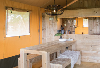 Gemütlicher Essbereich mit Holztisch in einem luxuriösen Glamping-Safarizelt in Nouvelle-Aquitaine.