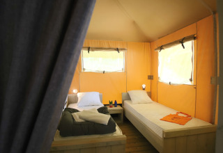 Intérieur de tente safari glamping avec deux lits simples à Les Truffières de Dordogne – La Bouquerie, Nouvelle-Aquitaine.