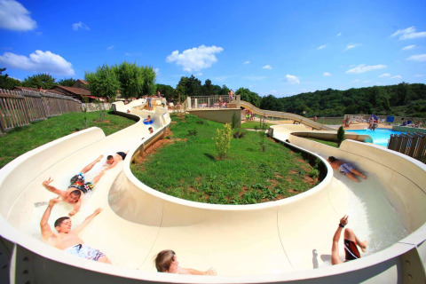 Bambini che si divertono su uno scivolo d'acqua a Les Truffières de Dordogne – La Bouquerie sotto il sole.