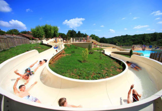 Kinder rutschen auf einer Wasserrutsche bei Les Truffières de Dordogne – La Bouquerie im Sonnenschein.