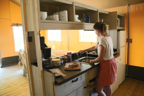 Vrouw doet de afwas in een moderne keuken op glamping Les Truffières de Dordogne – La Bouquerie – Safaritenten Nouvelle-Aquitaine.