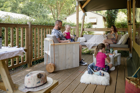 Familie entspannt auf einer Holzterrasse im Safarizelt bei Les Truffières de Dordogne – La Bouquerie.