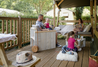 Famiglia che si rilassa su una terrazza glamping a Les Truffières de Dordogne – La Bouquerie in Nouvelle-Aquitaine.