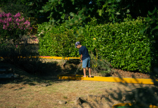 Niño jugando al minigolf entre vegetación en Les Truffières de Dordogne – La Bouquerie – Safaritenten.