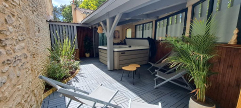 Overdekte buitenlounge met jacuzzi, ligstoelen en planten bij glamping Les Truffières de Dordogne.