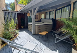 Outdoor lounge with hot tub, deck chairs and plants at Les Truffières de Dordogne glamping accommodation.