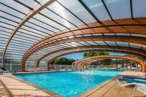 Indendørs swimmingpool med buet trætag på Les Truffières de Dordogne – La Bouquerie glampingplads i Nouvelle-Aquitaine.