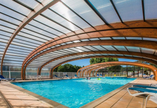 Überdachtes Schwimmbad in Les Truffières de Dordogne – La Bouquerie Safarizelten, Nouvelle-Aquitaine, mit Holzbögen.