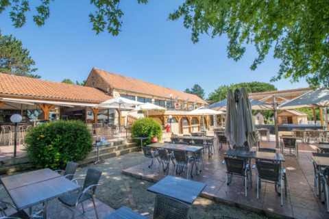 Buiten eetgedeelte met tafels en parasols bij Les Truffières de Dordogne – La Bouquerie safaritenten glamping.
