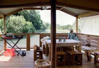 Buitenveranda van Les Truffières de Dordogne glamping met uitzicht op de rivier en groene natuur.
