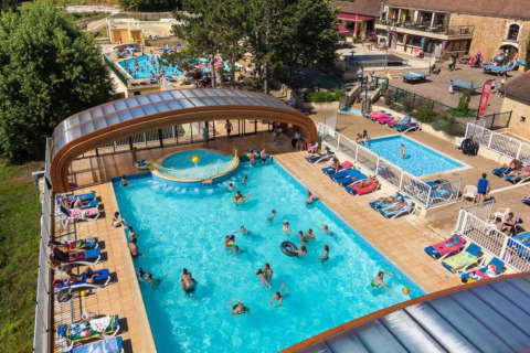 Vista aérea de Les Truffières de Dordogne – La Bouquerie glamping con piscinas y visitantes tomando el sol.
