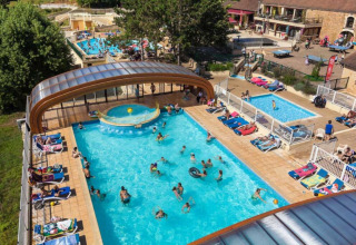 Aerial view of Les Truffières de Dordogne – La Bouquerie glamping with pools, lounge chairs, and guests relaxing.