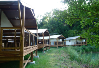 Glamping accommodation at Les Truffières de Dordogne with safari tents on wooden decks by the water.