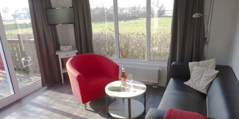 Interieur van een modern chalet op Camping Wackerballig, met knusse huiskamer en uitzicht op groene velden.