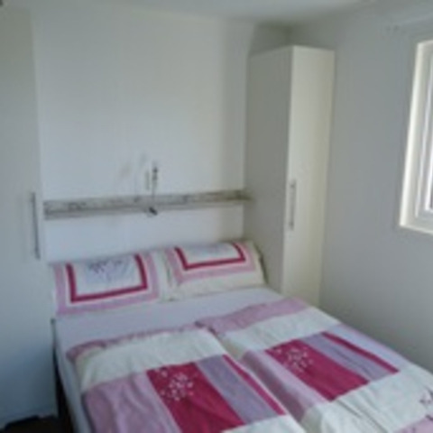 Bright bedroom in a glamping chalet at Camping Wackerballig featuring a double bed and modern decor.