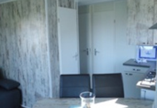 Vista interna di uno chalet moderno al Camping Wackerballig, Schleswig-Holstein, con tavolo da pranzo.