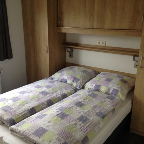 Binnenaanzicht van Chalets Sleeswijk-Holstein bij Camping Wackerballig met twee eenpersoonsbedden en kasten.
