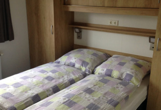 Innenaufnahme der Chalets Sleeswijk-Holstein auf Camping Wackerballig mit zwei Einzelbetten und Schränken.