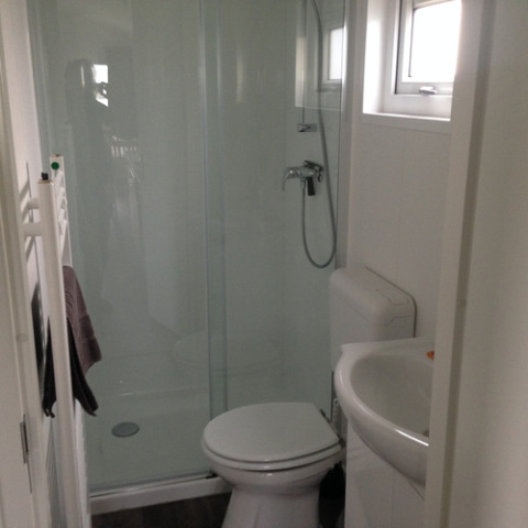 Moderne badkamer met douche, toilet en wastafel in een glamping chalet op Camping Wackerballig.