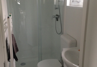 Moderne badeværelse med bruser, toilet og håndvask i glamping-indkvartering på Camping Wackerballig.