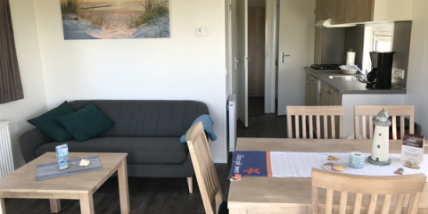 Vue intérieure de l'hébergement glamping Camping Wackerballig Chalets Sleeswijk-Holstein avec canapé et table à manger.