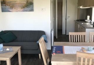 Indvendig udsigt over glampingbolig Camping Wackerballig Chalets Sleeswijk-Holstein med sofa og spisebord.