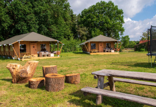 Glamping de Bosweide i Noord-Brabant med luksustelte, træmøbler og grønne omgivelser, sommerstemning.