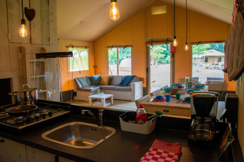 Interno di una tenda safari al Glamping de Bosweide, Noord-Brabant, con cucina e area lounge.