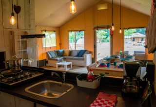 Interno di una tenda safari al Glamping de Bosweide, Noord-Brabant, con cucina e area lounge.