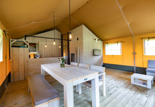 Interior view of luxury glamping lodge tent in Noord-Brabant, featuring dining table and cozy decor.