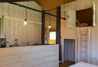 Innenansicht einer Glamping-Lodge mit hellem Holz, Hochbett und Küche bei Glamping de Bosweide, Noord-Brabant.
