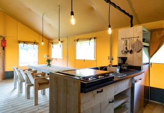 Vista interna di una tenda lodge glamping di lusso con tavolo da pranzo e cucina a Noord-Brabant, Paesi Bassi.